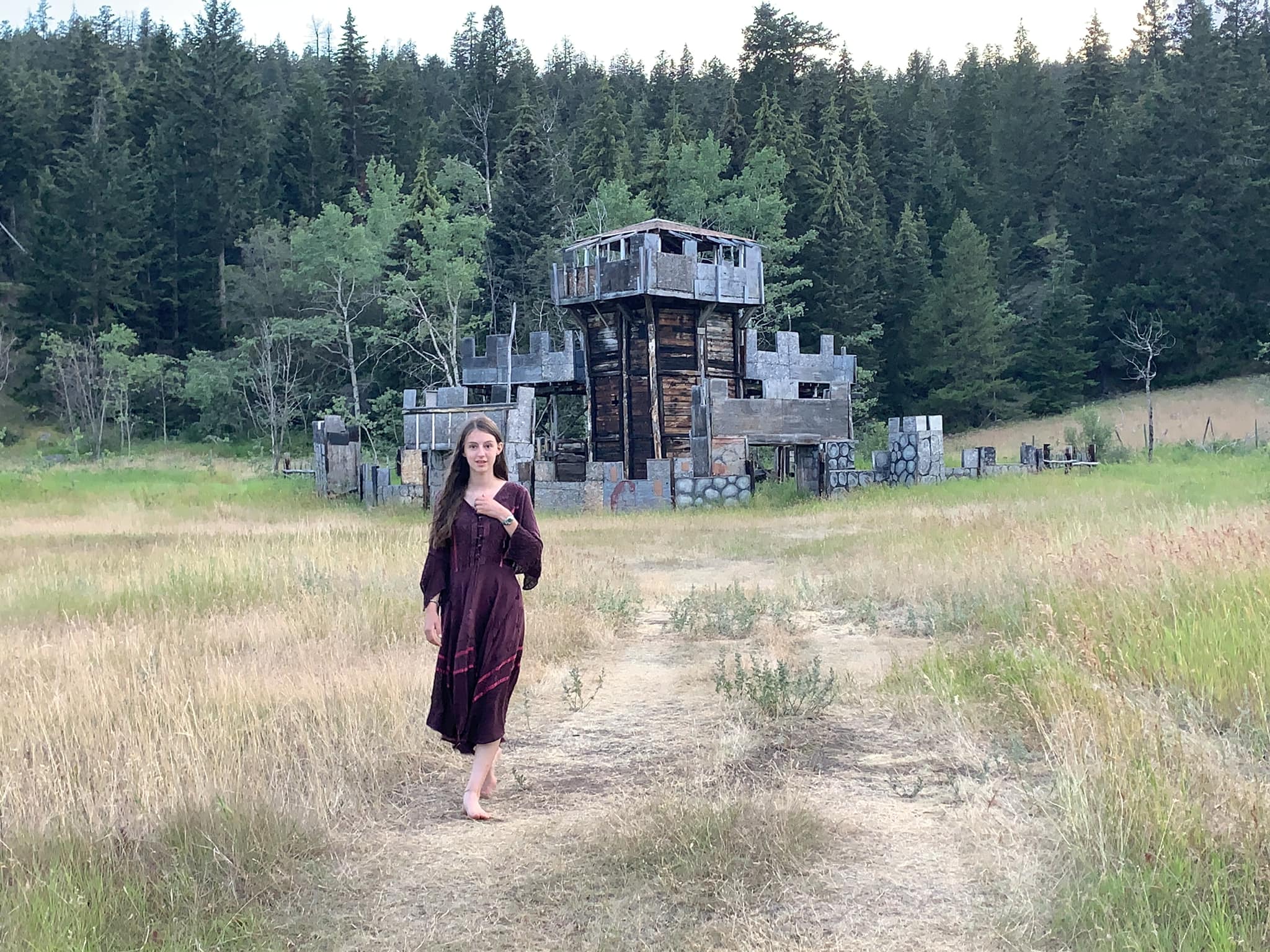 A woman in medieval attire standing in front of the wooden castle structure used during Clinton War